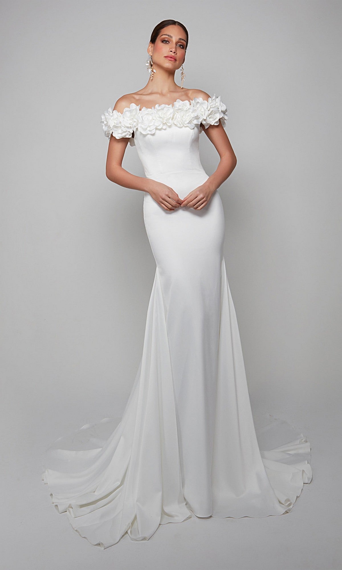A woman models the Alyce 7061 long formal dress, featuring an off-the-shoulder neckline with floral detailing and a sweeping train, posed against a plain background.
